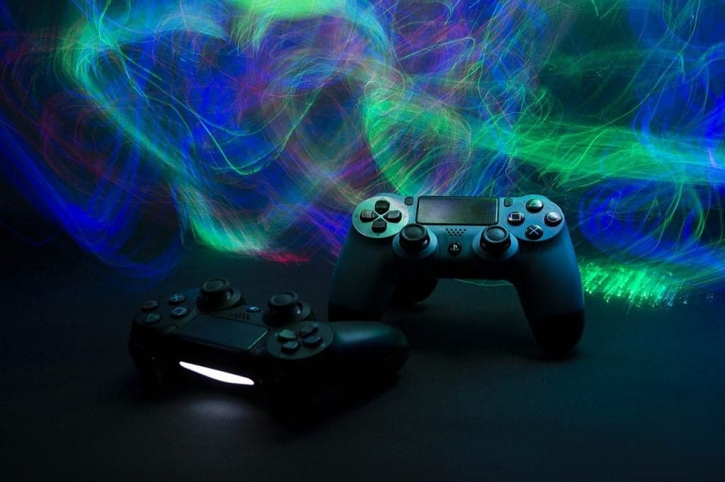 Two game controllers on a desk with colorful light trails